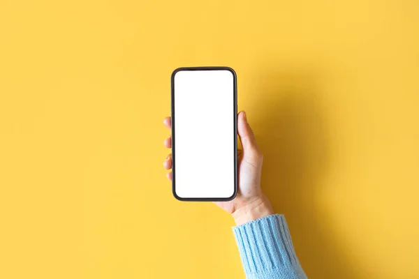 黄色の背景に白い画面で黒のスマートフォンを保持手を閉じます 携帯電話のフレームレスなデザインコンセプト — ストック写真