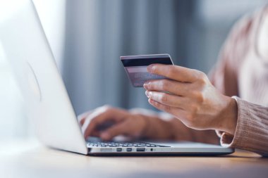 Online payment, Closeup Woman hands holding a credit card and using computer laptop for online shopping at home.