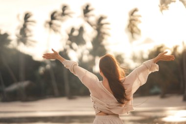 Summer beach vacation concept, Young woman with hat relaxing with her arms raised to her head enjoying looking view of beach ocean on hot summer day, copy space