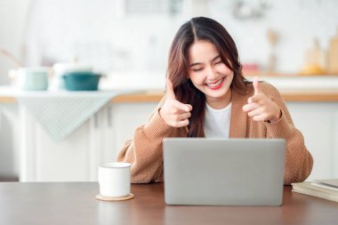 Mutlu, genç Asyalı kadın evde online iletişimden zevk alıyor, Wi-Fi kullanan kadın arkadaşlarıyla video konferansı yapıyor, açık dizüstü bilgisayarın önünde oturuyor, boşluğu kopyalıyor..