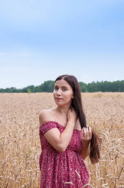 一个美丽的黑发女孩的画像 她的长发在田野里 长着红色连衣裙的玉米耳朵 — 图库照片