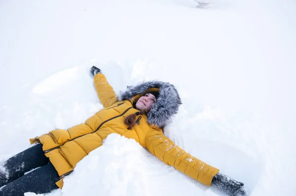 Дівчина Жовтій Куртці Капюшоном Лежить Снігу — стокове фото