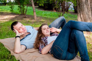 Genç bir çift, bir erkek ve bir kız, yazın parkta dinleniyorlar.