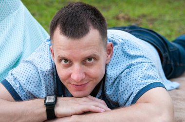 Tatmin olmuş bir adam yazın parkta çimlerin üzerinde yatıyor.