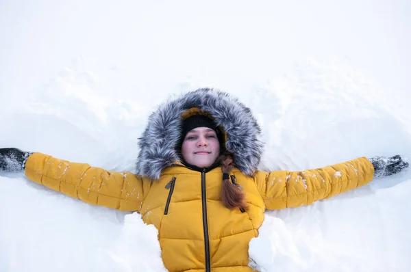 Дівчина Жовтій Куртці Капюшоном Лежить Снігу — стокове фото