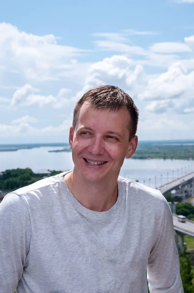 Bir yaz manzarasının arka planında gülümseyen genç bir adamın portresi