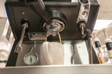 Doğal kahve yapmak için kullanılan kahve makinesi içeceği beyaz bardağa doldurur.