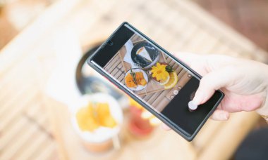 Kadın eli, sosyal medyaya tavsiye ve paylaşım için Tay tatlısıyla birlikte cep telefonu kullanıyor..