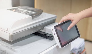 İş kadını, fotokopi makinesinin panelinde lazer parmak izi kartuşu işlemleri için elle düğmeye basıyor..