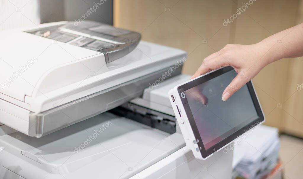 Business woman hand press button on panel of copy printer machine for process paperwork on laser print cartridge at the business office.