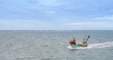 Chantaburi / THAILAND - 13, 2021: Teknede yüzen balıkçı, kıyıdaki yerel deniz ürünleri pazarında balık ararken, Chantaburi Tayland.