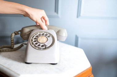 Kadın el ele tutuşması. Yirminci yüzyılın eski gri telefon seti klasik ahşap masa içinde duruyor..