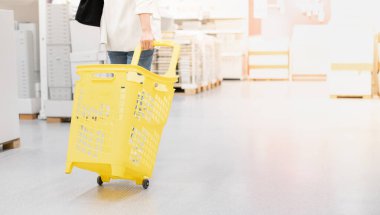 Kadın, iç mekan için dekorasyon malzemesi almak için sarı plastik tramvayı çekiyor..