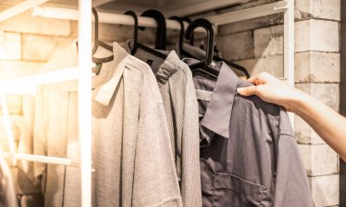 Erkek el, bir mağazadaki kumaş mağazasının rafında işaretli desenli pamuk polo gömleği için kıyafet seçiyor. Kontrol fiyatı, indirim ve giyim ürünlerinin tanıtımı.