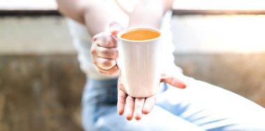 Oturma odasında dinlenirken bir fincan çay tutan bir kadın. Boşluğu kopyala.