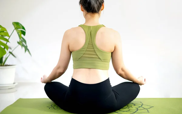 女人在家里练习瑜伽 冥想坐在绿色瑜伽垫上 — 图库照片