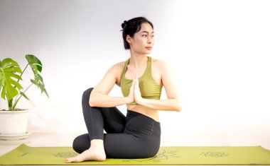Kadınlar evde meditasyon yapmak ve egzersiz yapmak için yeşil yoga minderinde yoga yaparlar..