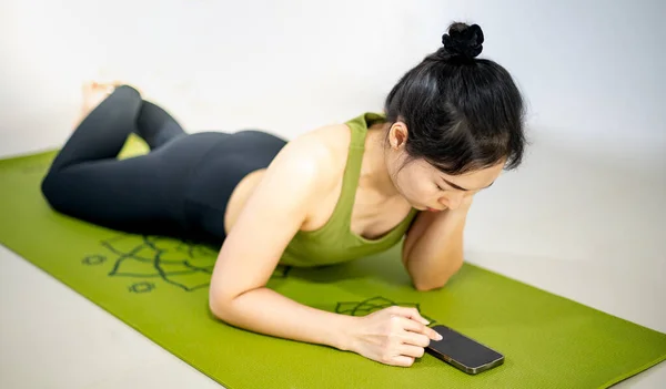 Las Mujeres Juegan Móvil Sientan Esterilla Yoga Verde Mientras Descansan — Foto de Stock