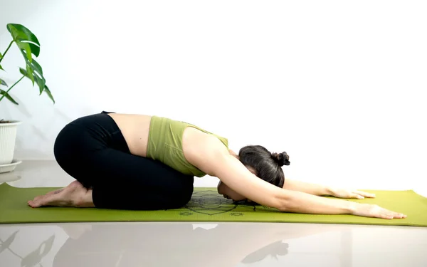 女人在绿色瑜伽垫上做瑜伽 以便在家里冥想和锻炼 — 图库照片