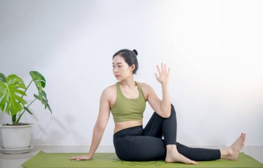 Kadınlar evde meditasyon yapmak ve egzersiz yapmak için yeşil yoga minderinde yoga yaparlar..