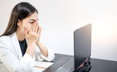 Asyalı gençler evlerinde dizüstü bilgisayarın önünde otururken işten dolayı stres yaşıyorlar. Stresli çalışan veya öğrenci kavramı çalışmaktan bıktı, çevrimiçi sorun hakkında endişelendi.