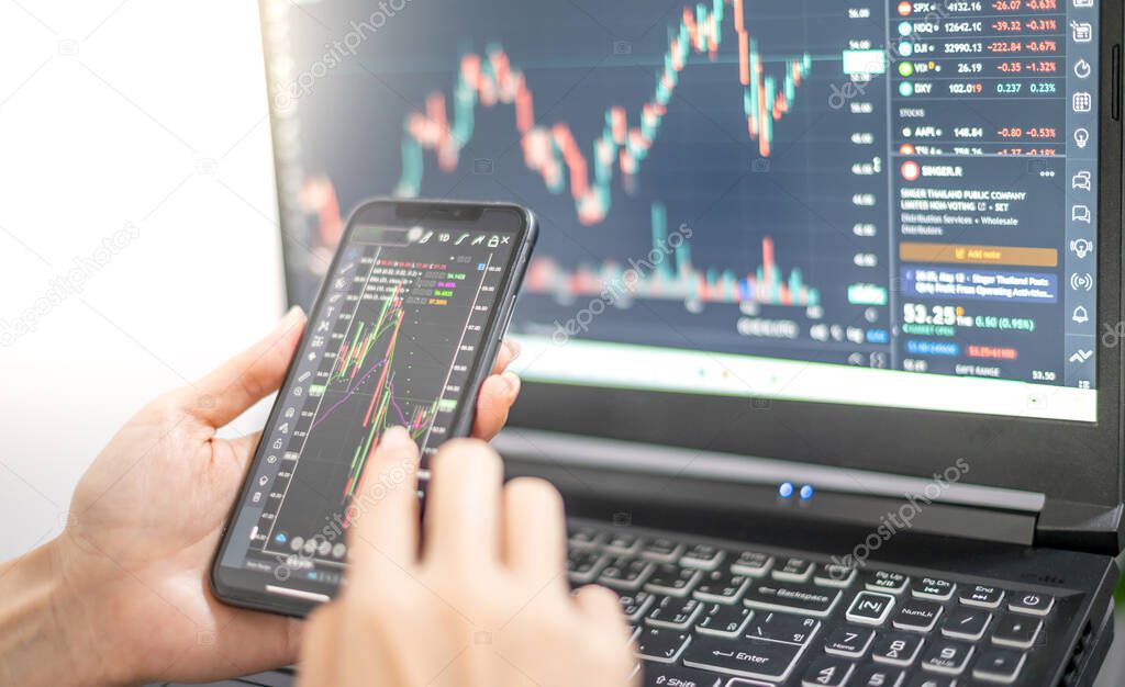 Female trader investor broker analyst holding a smartphone in hand analyzing stock market trading charts indexes data checking price using mobile stockmarket exchange app while the World economic still recession.