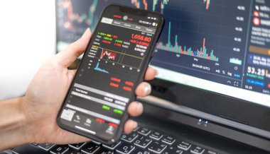 Female trader investor broker analyst holding smartphone in hand analyzing stock market trading charts indexes data checking price using mobile stockmarket exchange app while the World economis still recession.