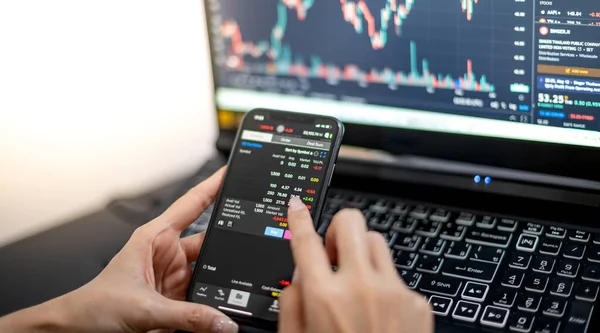 Female trader investor broker analyst holding smartphone in hand analyzing stock market trading charts indexes data checking price using mobile stockmarket exchange app while the World economis still recession.