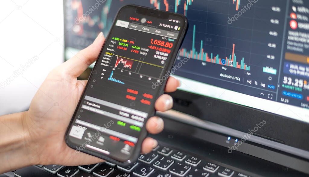 Female trader investor broker analyst holding smartphone in hand analyzing stock market trading charts indexes data checking price using mobile stockmarket exchange app while the World economis still recession.