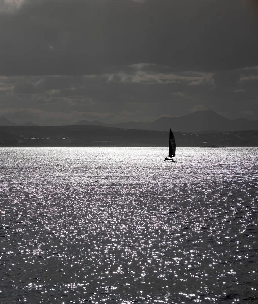 A sailboat sets sail under overcast clouds in Mossel Bay, Garden Route, South Africa