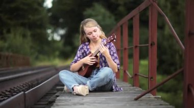 Demiryolunda gitarı olan genç bir kadın.