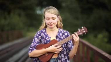 Parkta gitar çalan genç bir kadın.