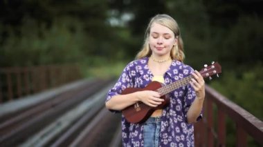 Parkta gitar çalan genç bir kadın.