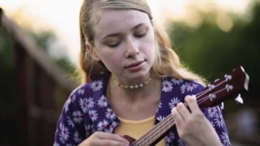 Evde gitar çalan neşeli bir kız. Mutlu kadın dışarıda telli çalgılarla müzik çalışıyor. Başarıyı kutlayan tatmin olmuş gitarist. Genç bayan elleriyle evet işareti yapıyor.