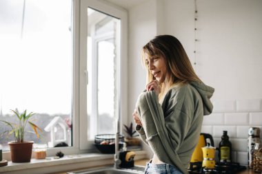 Mutfakta bir bardak suyla genç bir kadın.