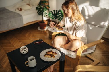 Bir fincan çay ve kruvasanla güzel genç bir kadın.