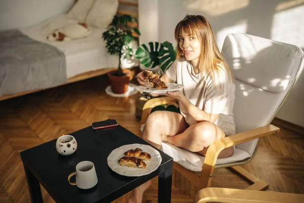 Kafede çay ve kruvasanla güzel genç bir kadın.