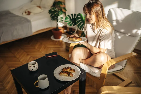 Genç bayan mutfakta çay ve kruvasanla