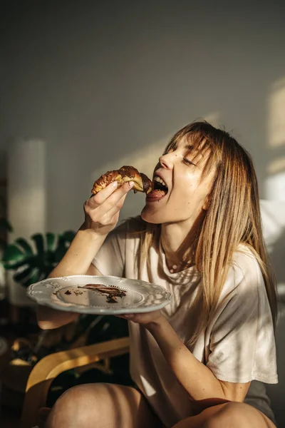 Hamburger yiyen ve bira içen genç bir kadın.