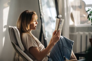 Kütüphanede kitap okuyan genç bir kadın.