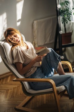 Odada kitap okuyan güzel genç bir kadın.