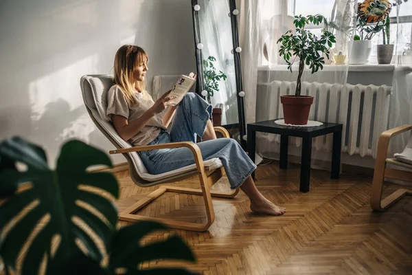 Güzel genç bir kadın modern ofiste kanepede oturuyor ve kitap okuyor.