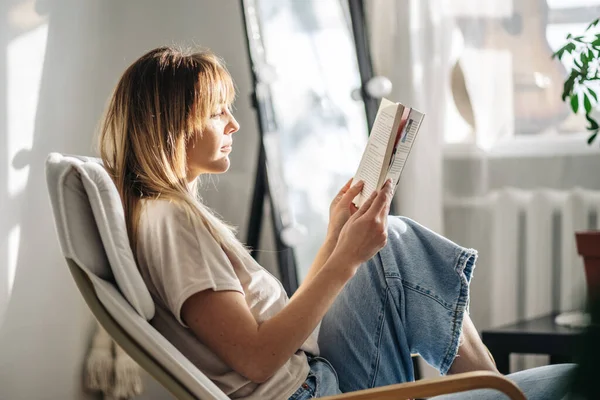 Kütüphanede kitap okuyan genç bir kadın.