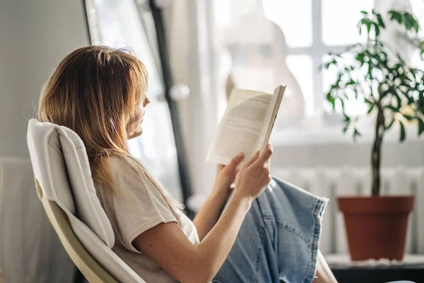 Kafede kitap okuyan genç bir kadın.