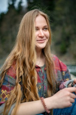 Yeşil ceketli ve arka planda eşarbı olan uzun saçlı güzel bir genç kadının portresi.