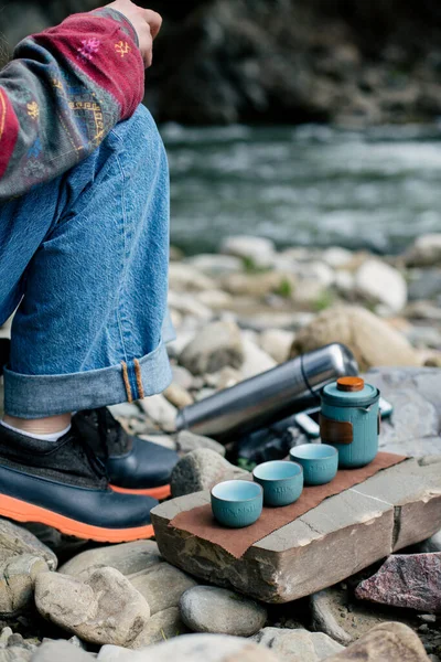 Sırt çantalı bir adam ve nehirde bir termos.