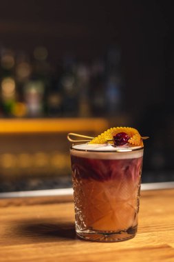 Tahta bir masanın üzerinde buz küpleri olan bir bardak kokteyl.