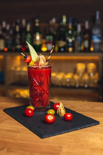 Bardakta kırmızı ve portakal suyu ve ahşap bir masada pipetle kokteyl.