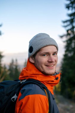 Sırt çantalı genç adam dağlarda yürüyüş yapıyor.