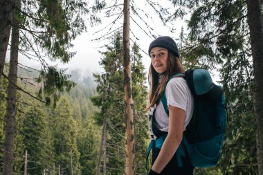 Sırt çantalı genç bir kadın ormanda yürüyüş yapıyor. Doğa ve seyahat.